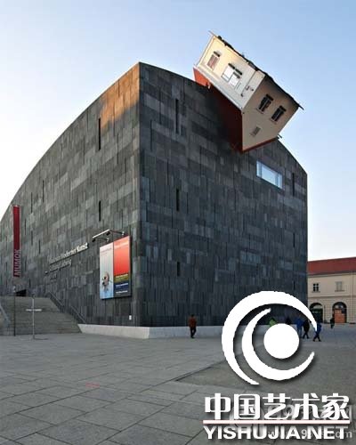 艺术家 Erwin Wurm 把一幢倒置的房子安装在维也纳的 Moderner Kunst 艺术馆房顶，他的艺术装置把整个艺术馆都变成了一件艺术品。
